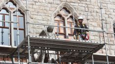 Operarios de obra montando los andamios que esconderán la restauración de la Casa Botines de Gaudí Operarios de obra montando los andamios que esconderán la restauración de la Casa Botines de Gaudí