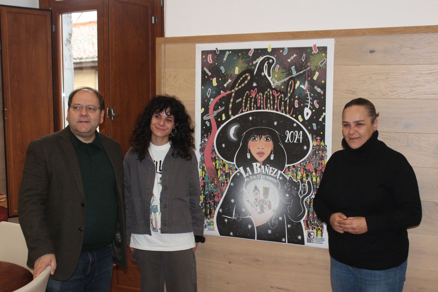 Javier Carreras, Laura Blanco y Carmen Macho junto al cartel anunciador del Carnaval 2024 de La Bañeza