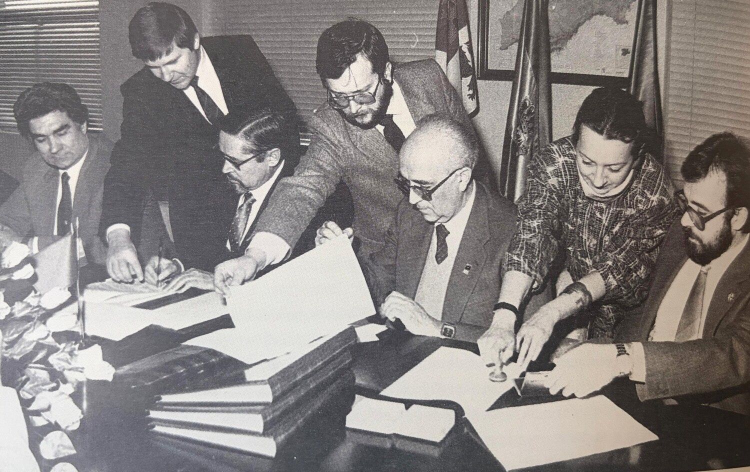 Manuel García Álvarez, en el centro de pie sujetando una hoja, durante una firma de un convenio en la Universidad